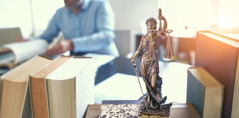 Voluntario trabajando en el escritorio con libros de leyes y la estatua de la justicia